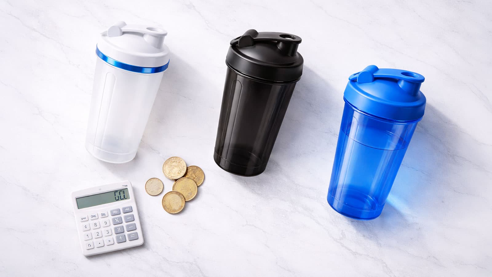 Drei Protein Shaker in verschiedenen Farben mit Muenzen auf Marmoroberflaeche – Preisguide